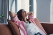 © Daniel - Relaxed serene pretty young woman feel fatigue lounge on comfortable sofa hands behind head rest at home, happy calm lady dream enjoy wellbeing breathing fresh air in cozy home modern living room