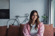 © Daniel - Smiling young woman relaxing on a comfortable couch at home, enjoying a calm and peaceful moment indoors, capturing everyday lifestyle, comfort, and positive wellbeing in a cozy living room setting