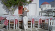 © Krakenimages.com - Woman standing with hands on head by checkered restaurant tables and white chairs on street; serenity.