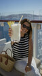 © Krakenimages.com - Woman young hispanic brunette holding cocktail glass with pineapple slice and straw on cruise terrace by glass railing, smiling; relaxation escape summer.