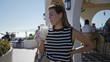 © Krakenimages.com - Woman holding a pina colada cocktail on a cruise terrace, sipping from a straw and smiling toward camera; relaxed leisure.