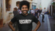 © Krakenimages.com - Smiling african american man in security uniform standing confidently on a busy city street, suggesting a safe urban environment.
