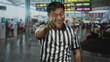 © Krakenimages.com - Young chinese man referee points finger to camera in busy airport terminal; confidence authority presence.