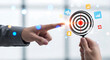 © Mizanby - Person pointing at a dartboard representing a goal, with business-related icons floating around, symbolizing success and strategic planning