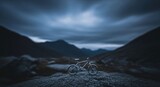 Miniature bicycle on a rocky outcrop against a mountain landscape under a stormy sky