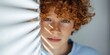 © Andrii Zastrozhnov - Redheaded male caucasian child with freckles and curly hair bathed in blinds sunlight looking thoughtful close-up portrait