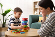 © New Africa - Mother and her son playing with educational toy at wooden table indoors