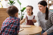 © New Africa - Smiling mother and her children playing with educational toys at wooden table indoors