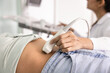 © fizkes - Close up female doctor using ultrasound probe on patients abdomen, performing diagnostic examination for medical evaluation, scanning, checking internal organs and monitor possible pregnancy in clinic