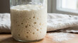 © l1gend - Close-up of sourdough starter in a glass jar with active bubble culture visible, no faces, no text, artisan fermentation concept for bakery brand or culinary editorial, commercial use