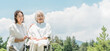 © buritora - A senior woman in a wheelchair and another woman assisting her in a park (caregiving, parent-child relationship, nursing home)