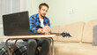 © Mariia - Man learning to play guitar with online music course at home. Time for hobby