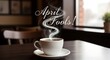 © BangTeko - Steaming coffee cup on table with april fools text in decorative font
