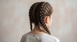 © thenort - A young person's head with two braided hairstyles, facing away from the camera