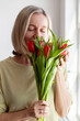 © Tatyana Gladskih - Happy Mother's Day and Women's Day. Charming woman sitting with bouquet of tulips in the living room at home