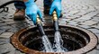 © thenort - Person in gloves uses hoses to direct water into a sewer drain in a cobblestone street