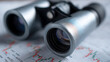 © photo for everything - Silver Binoculars with Textured Grip Rest on Financial Charts, Focusing on Market Data for Business Strategy and Investment Analysis