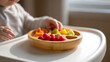 © photo for everything - Little hands explore and select vibrant, healthy fruit pieces from a bamboo sectioned plate, promoting independent eating and nutritious child development