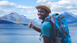 © arrowsmith2 - Cheerful African Traveler Giving Thumbs Up while Hiking in Beautiful Lake and Mountain Landscape