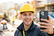© Meow Creations - Smiling male construction worker wearing a yellow hard hat while taking a selfie on a smartphone