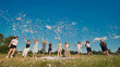 © Довидович Михаил - High school graduates joyfully tossing colorful confetti in a sunny field to celebrate their achievement