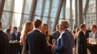 © AndiAzis - Business professionals engaging in networking and conversation at a modern corporate event in a glass-walled venue with natural sunlight and contemporary architecture