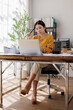 © David - A young woman in a yellow sweater is engrossed in her work at a desk filled with documents and a laptop, showcasing productivity and concentration in a bright office atmosphere.