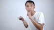 © Nayaka - Young asian man holding a key and making a gesture to keep silent isolated in white