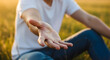 © xaras - Person sitting in field with outstretched hand showing palm