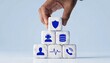 © hasanserta - Hand placing a cube with a shield on a pyramid of cubes with various