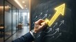 © Mst. Tahamina Akter - Hand drawing golden arrow graph on blackboard indicating financial growth and success in modern office
