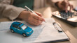 © Garun Studios - Customer signing car purchase agreement with auto loan and insurance policy, symbolizing vehicle finance, ownership transfer and dealership transaction in automotive business.