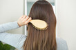 © KMPZZZ - Health hair care, beauty concept. Asian woman hand holding hairbrush and brushing, girl combing long straight hair in morning routine after wash and treatment at home