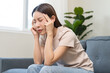 © KMPZZZ - Depressed anxiety asian young woman frustrated hand on head, touching her temples, suffering stressed, sick, tired, crisis on sofa from headache, migraine pain tension problem health care concept.