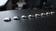 © DhanShalik - Reflective Liquid Metal Chrome Droplets in a Diagonal Row on Carbon Fiber Background