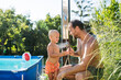 © Halfpoint - Son and father under shower by the pool on sunny summer day.