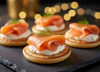 © Jim - Smoked salmon appetizers arranged on slate. Small cornbread cakes topped with cream cheese, salmon, and dill. Cozy bokeh lights add festive atmosphere for parties or events. Gourmet Party Appetizers