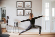 © Westend61 - Woman practising yoga at home, warrior pose