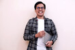 © Nurma - Man smiles warmly while holding a laptop. He wears glasses and a casual shirt. Background is plain, bright, and neutral. Ideal for tech, education, or remote work visuals