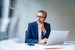 © Westend61 - Business manager working at laptop in modern office thinking