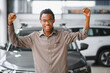 © Serhii - Young african american handsome man choosing a car in a car showroom