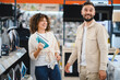 © Serhii - Couple exploring options in electronics store