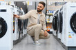 © Serhii - Customer choosing washing machine in electronics store