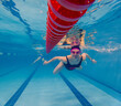 © phpetrunina14 - Underwater swimmer training in pool beside red lane line Copy Space