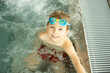 © Tomsickova - Child, taking swimming lessons in a group of children in indoor pool