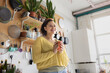 © ReeldealHD images - Female college student Holding Mug and Smiling in Cozy Kitchen