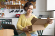 © ReeldealHD images - Happy young female entrepreneur looking at order details from e-commerce site and preparing parcels to ship