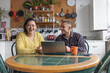 © ReeldealHD images - College students laughing together while using laptop in a kitchen