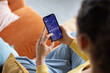 © ReeldealHD images - Over the shoulder view of young woman with friend checking financial data with mobile banking app on a smartphone