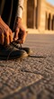 © niswati - Man Tying Shoelaces on Cobblestone Street.